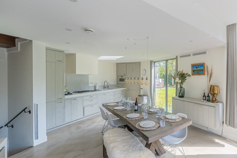 Dining room of Duynzoom Villa 5 in De Koog, Texel, with a large table and views of the green garden.
