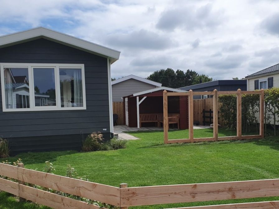 Chaletpark Bregkoog, De Koog, Texel: Modern chalet with green garden and wooden fence.