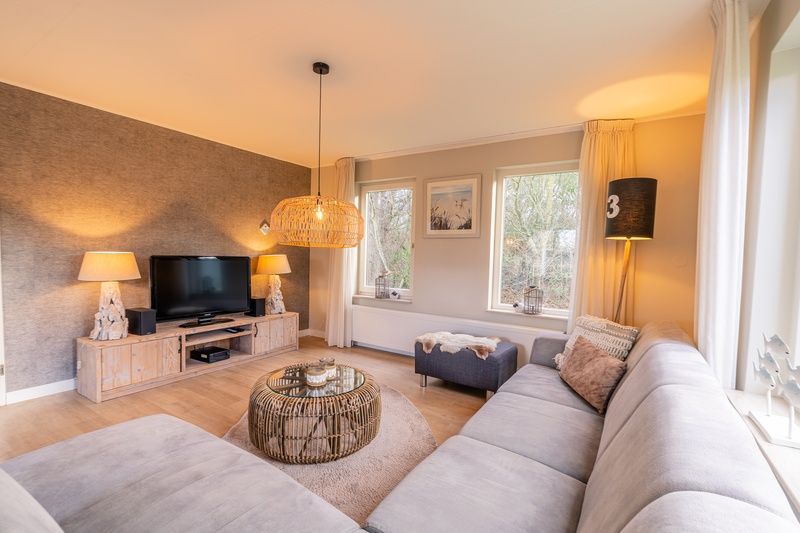 Gemuetliches Wohnzimmer des Ferienhauses Kamperfoelie 73 in De Koog, Texel mit bequemen Sofas und moderner Einrichtung.