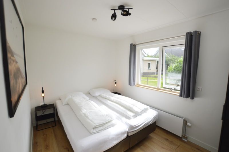 Ferienhaus Stappeland 203 in De Koog Texel, helles Schlafzimmer mit Doppelbett und Gartenblick.