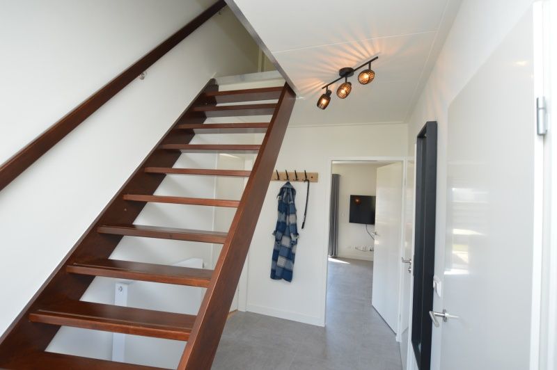 Eingang zum Ferienhaus Stappeland 203 in De Koog Texel, mit Holztreppe und moderner Beleuchtung.