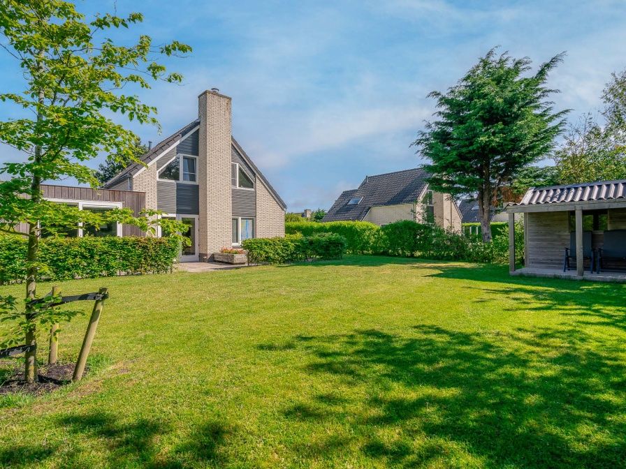 Vacation home Honeysuckle 93 with sauna in De Koog, Texel, surrounded by green garden and terrace.