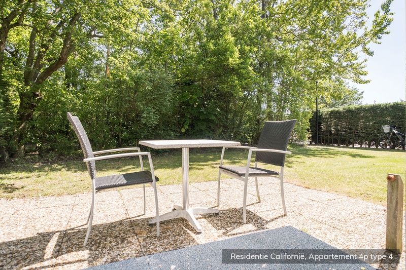 Sunny terrace at Type 4 vacation home, De Koog, Texel. Perfect for outdoor dining amidst nature.