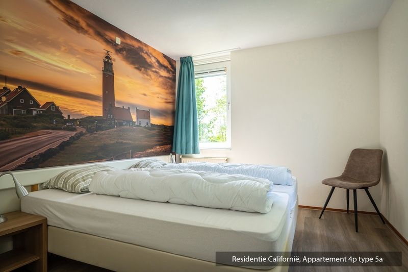 Geraeumiges Schlafzimmer im Ferienhaus Typ 5A, De Koog, Texel, mit schoener Leuchtturmtapete.