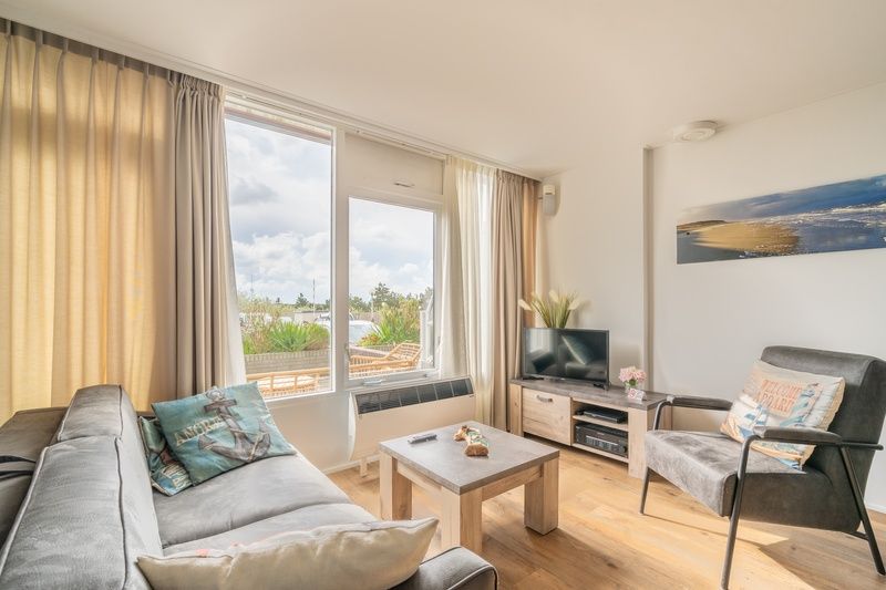 Helles Wohnzimmer des Appartements Juliana 076 Eilandzicht in De Koog, Texel, mit bequemen Sitzmoebeln und moderner Einrichtung.