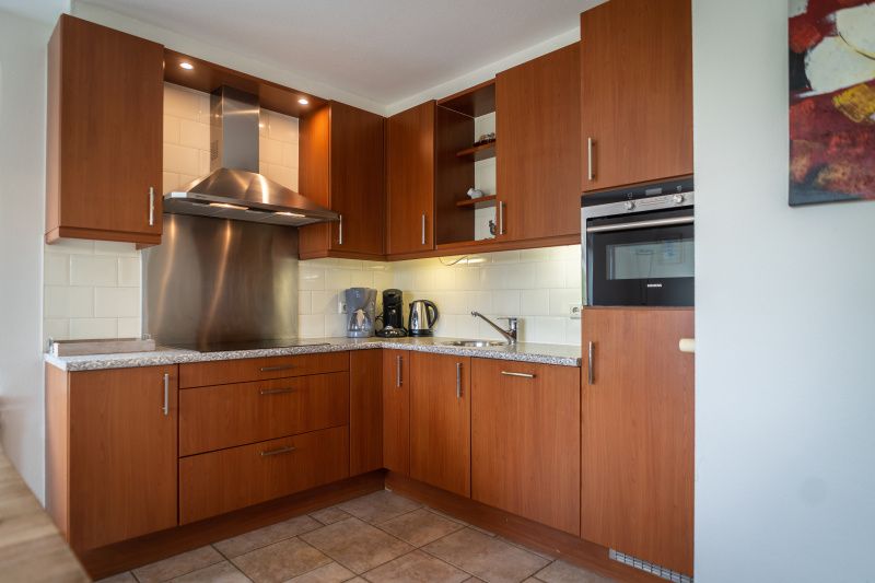 Modern kitchen in Villa 304, De Koog, Texel with wooden cabinets and complete kitchen appliances.