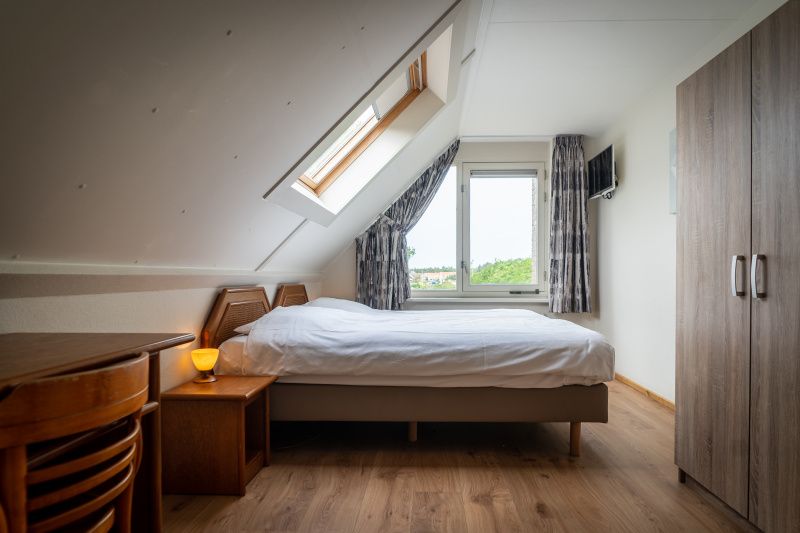 Spacious bedroom in Villa 304, De Koog, Texel with skylight and beautiful views of nature.