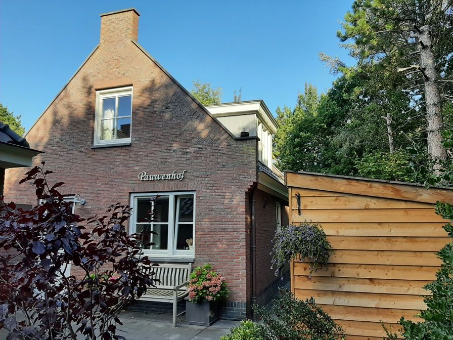 Pauwenhof Texel vacation home in De Koog with charming facade and green surroundings.