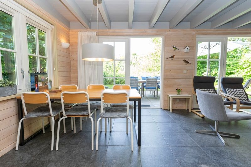 Spacious dining area in Het Boshuis, Vakantiepark Het Oude Dijkje, De Koog, Texel overlooking the green garden.