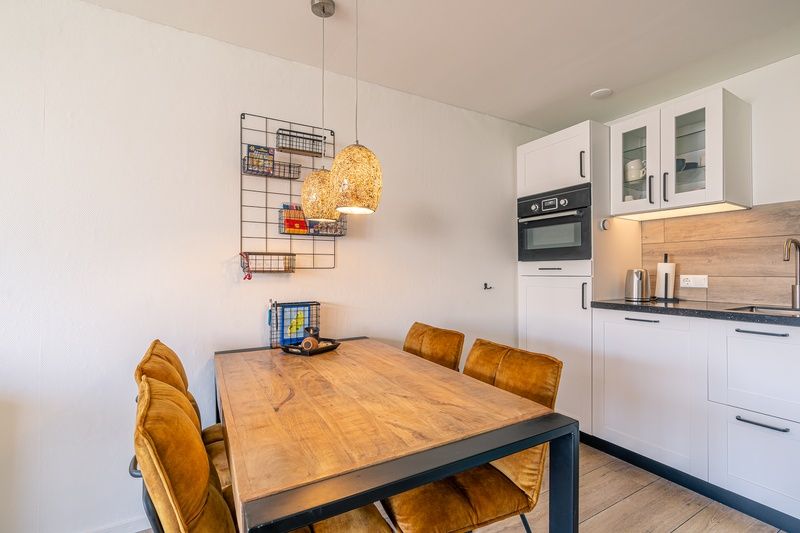 Esszimmer im Appartement Anna 220, De Koog, Texel mit Holztisch und stimmungsvoller Beleuchtung.