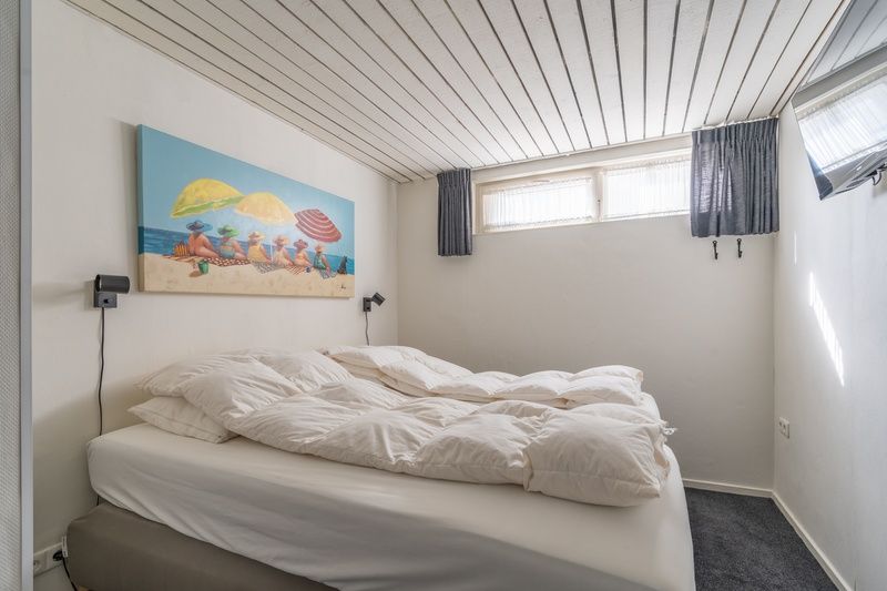 Gemuetliches Schlafzimmer im Appartement Anna 220, De Koog, Texel mit grossem Bett und Kunstdekoration.