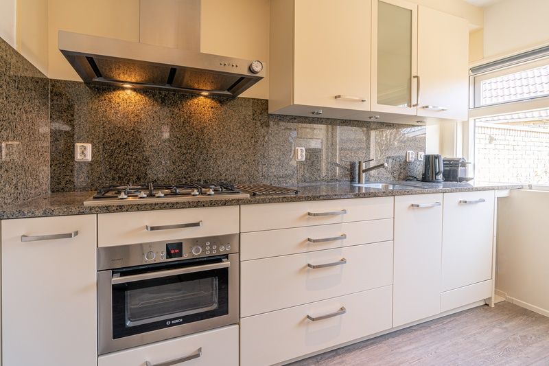 Moderne Kueche im Ferienhaus De Zandduyn, De Koog, Texel, mit Granitarbeitsplatte und Einbaugeraeten.