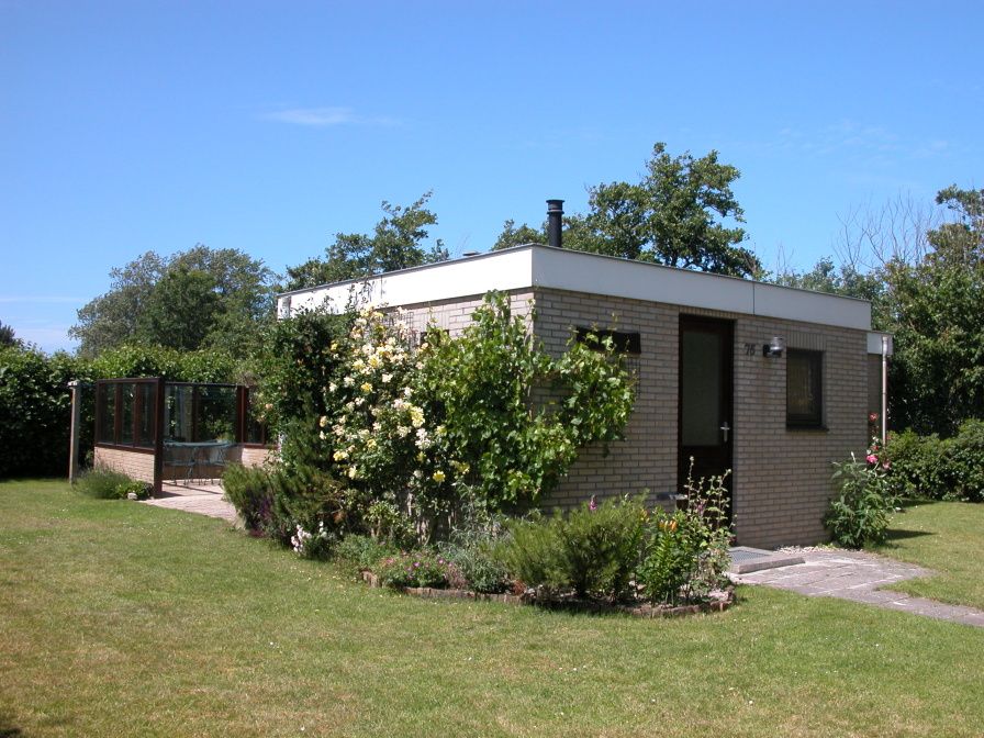 Bungalow Oud Vredelust 75 in De Koog, Texel, surrounded by green nature and flowers.