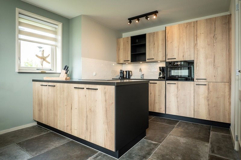 Moderne Kueche des Landhuis Ferienhauses in De Koog, Texel mit Holzschraenken und Geraeten.