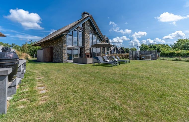 Vacation home in De Koog Texel with spacious garden and deck chairs, ideal for relaxation on the Wadden Islands.