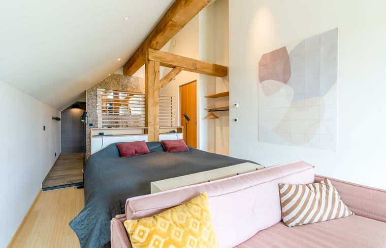 Bedroom with wooden beams and artistic decoration in Holiday home in De Koog Texel, for a unique stay on the Wadden Islands.