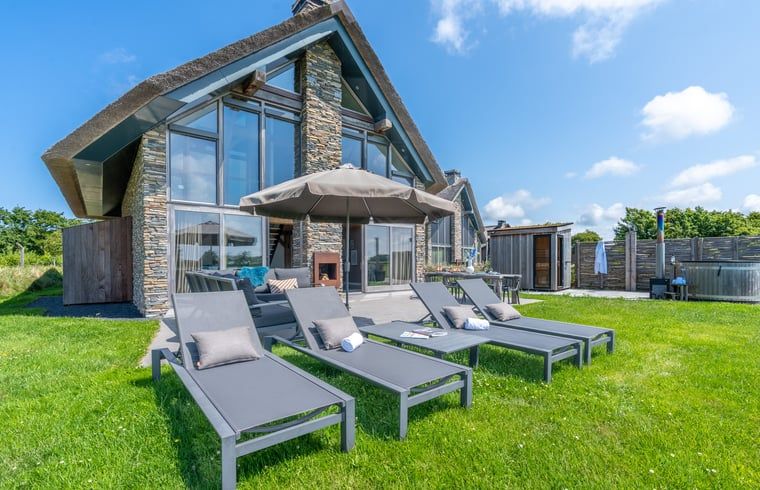 Spacious garden with deck chairs and parasol in Holiday home in De Koog Texel, ideal for sunbathing on the Wadden Islands.