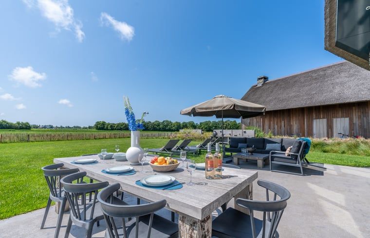 Outdoor area with large dining table in Holiday home in De Koog Texel, ideal for cozy meals on the Wadden Islands.