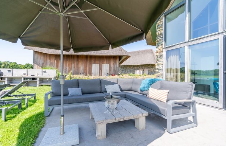 Sitting area with parasol and cushions in Holiday home in De Koog Texel, offers comfort on the Wadden Islands.