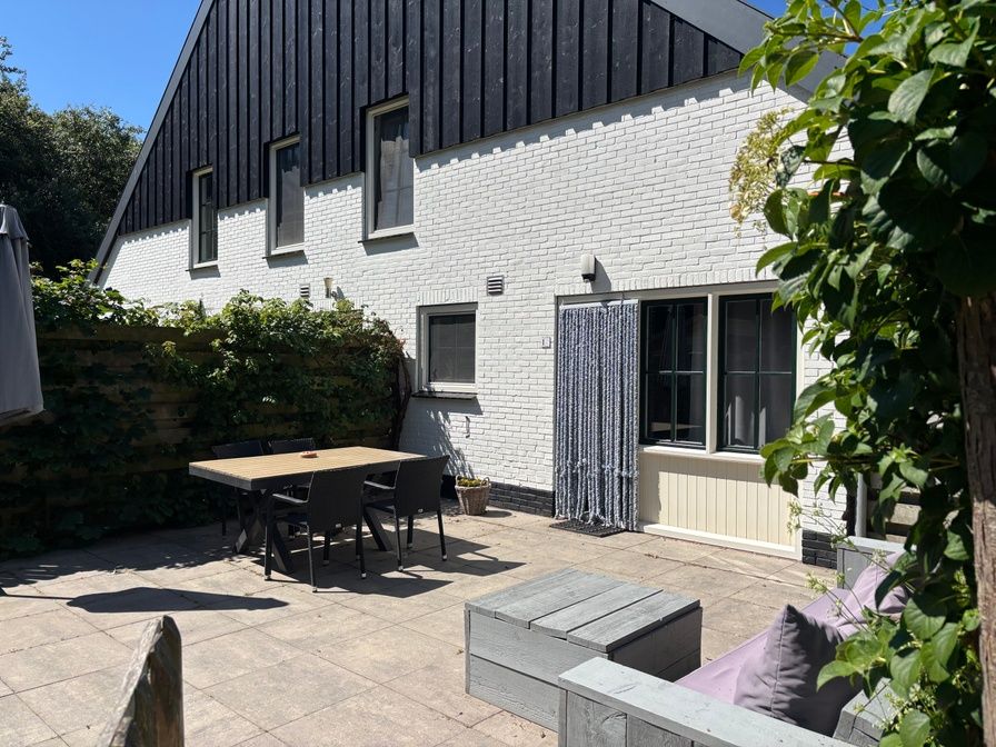 Spacious terrace at vacation home Stormvogel in De Koog, Texel with dining table and lounge sofa.