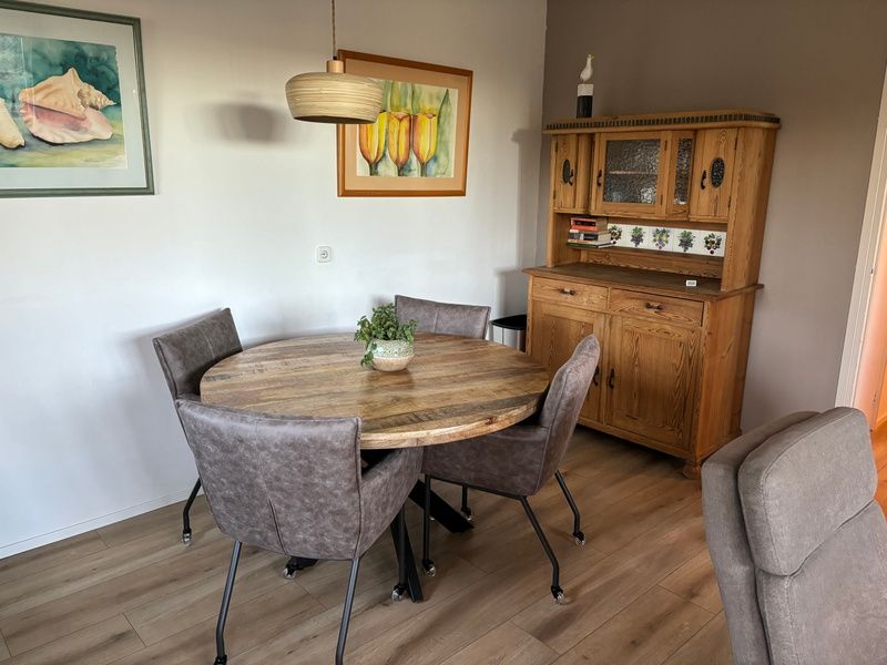 Dining area in Stormvogel, vacation home in De Koog, Texel with round table and wooden cabinet.