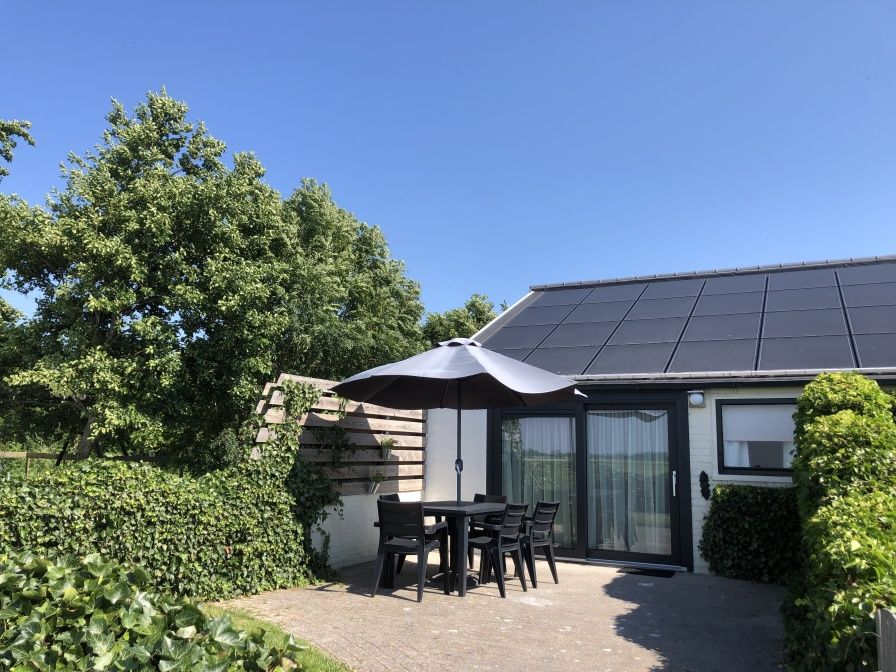 Spacious terrace at Bungalow 2 in De Koog, Texel with comfortable seating surrounded by green nature.