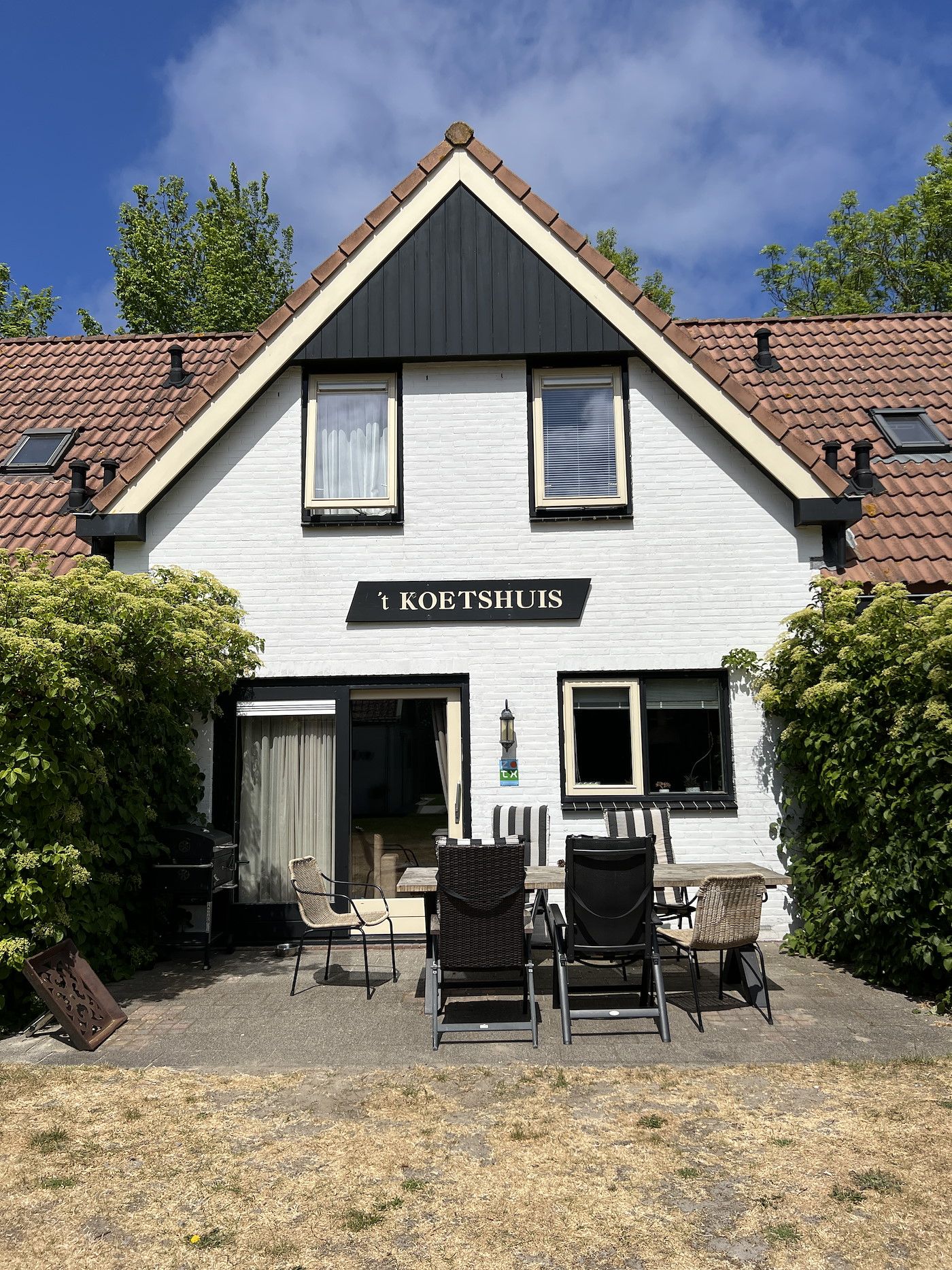 Ferienhaus Koetshuis 2 in De Koog, Texel mit sonniger Terrasse und gruener Umgebung.