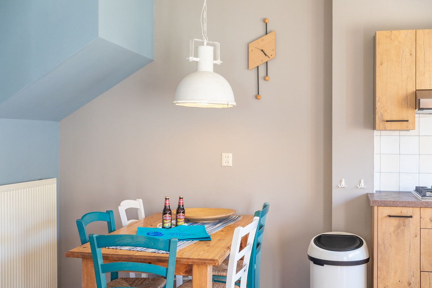 Essecke im Koetshuis 2, Texel mit Holztisch und bunten Stuehlen.