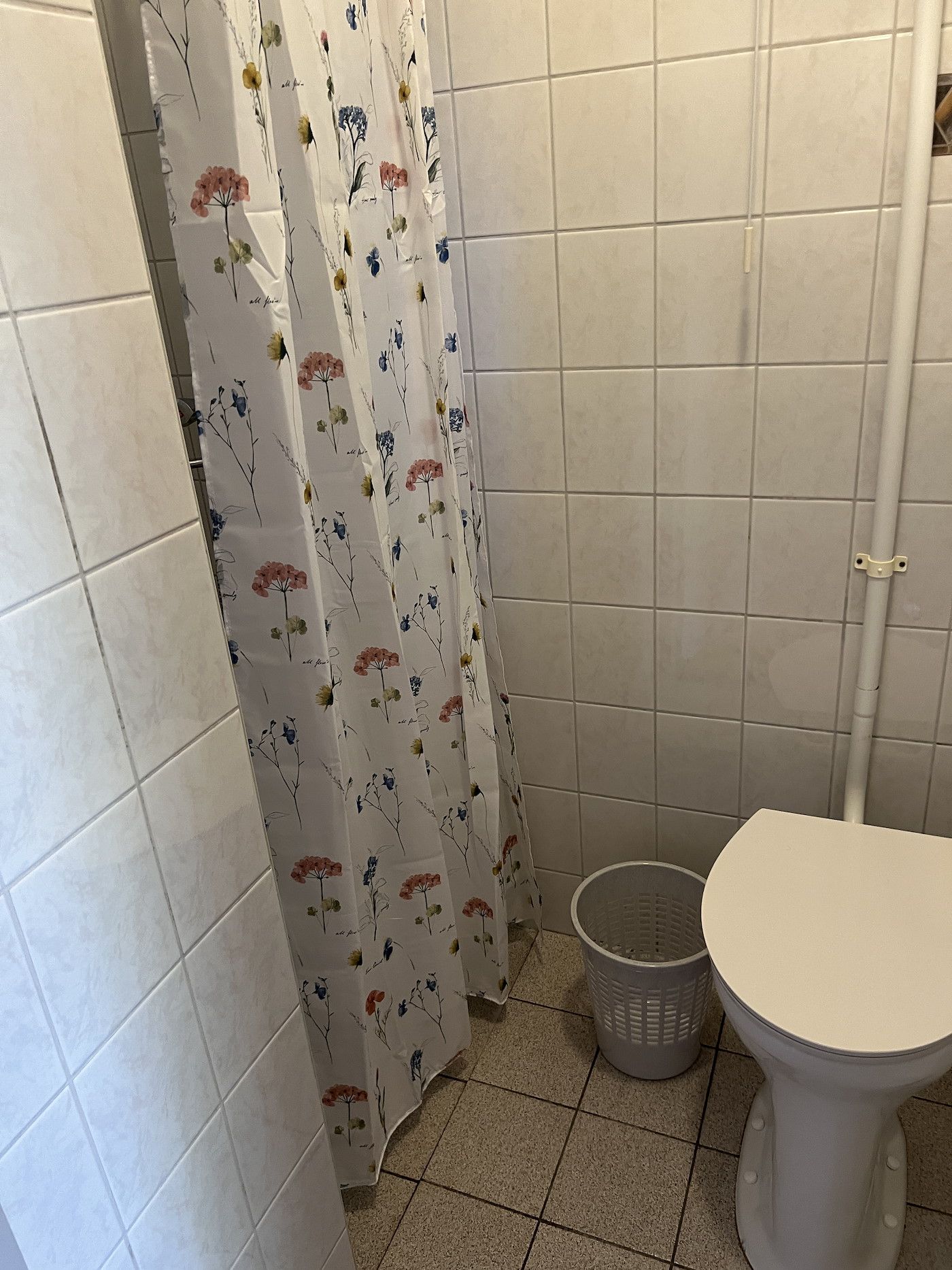 Badezimmer im Koetshuis 2, Texel mit Dusche und buntem Duschvorhang.
