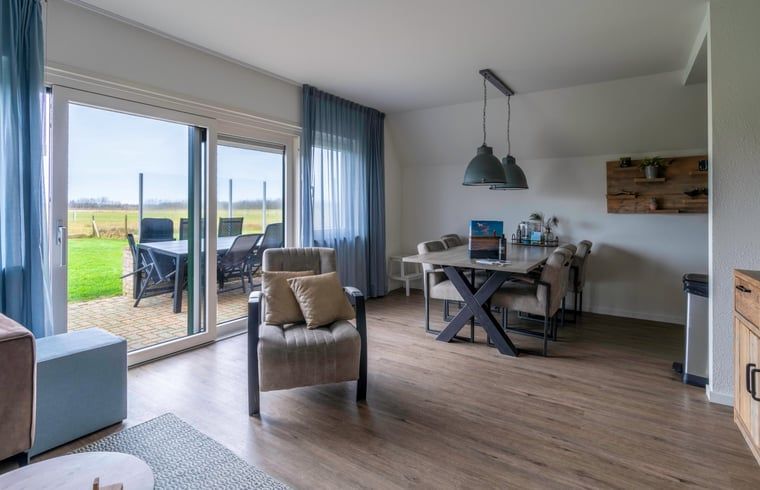 Offener Wohn- und Essbereich im Ferienhaus in De Waal, Texel mit Zugang zur Terrasse und Blick auf die Landschaft.