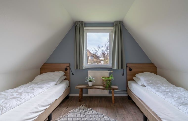 Schlafzimmer mit zwei Einzelbetten und Gartenblick im Ferienhaus in De Waal, Texel fuer einen erholsamen Aufenthalt.