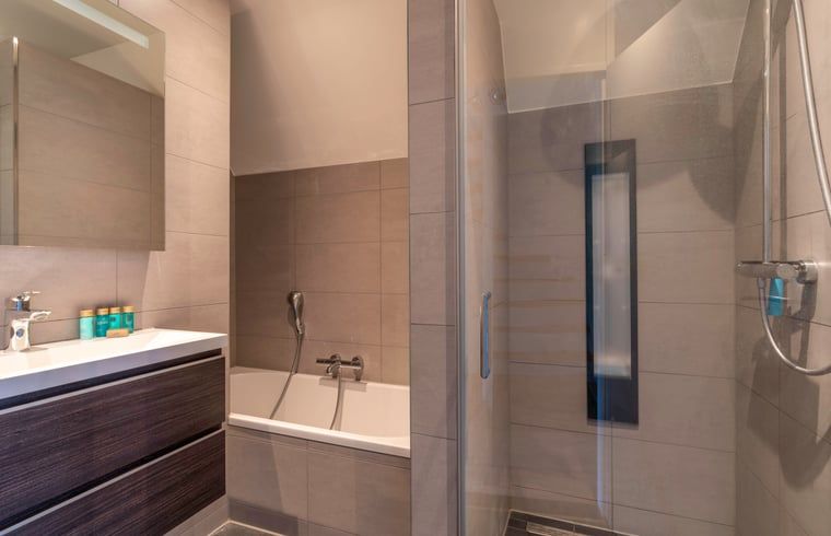 Modernes Badezimmer mit Badewanne und Dusche im Ferienhaus in De Waal, Texel fuer ein komfortables Ferienerlebnis.