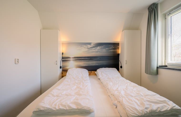 Schlafzimmer im Ferienhaus in De Waal, Texel mit Doppelbett und beruhigendem Stranddekor.