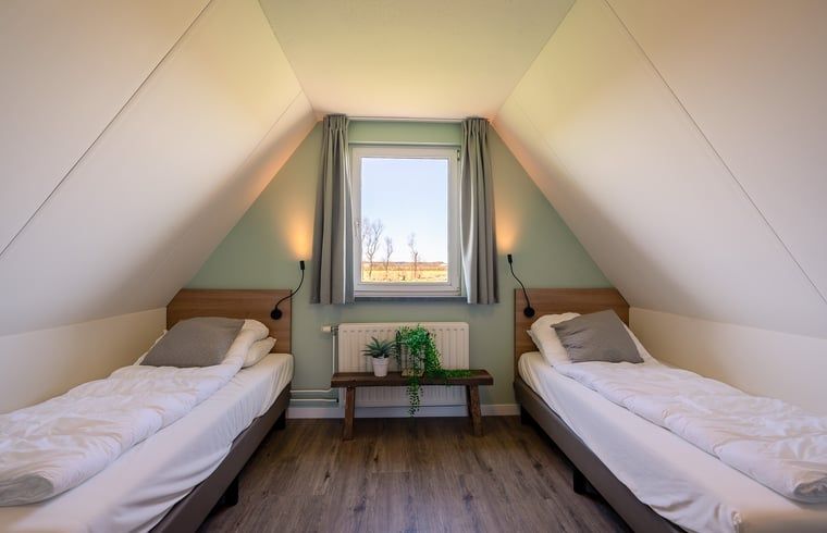 Zweites Schlafzimmer im Ferienhaus in De Waal, Texel mit zwei Einzelbetten und Blick auf die Natur.