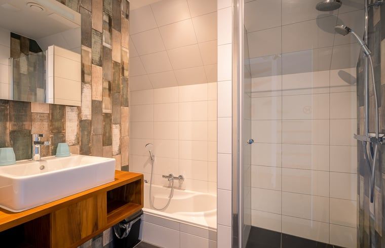 Modernes Badezimmer in einem Ferienhaus in De Waal, Texel, mit Dusche, Badewanne und stilvollen Kacheln.