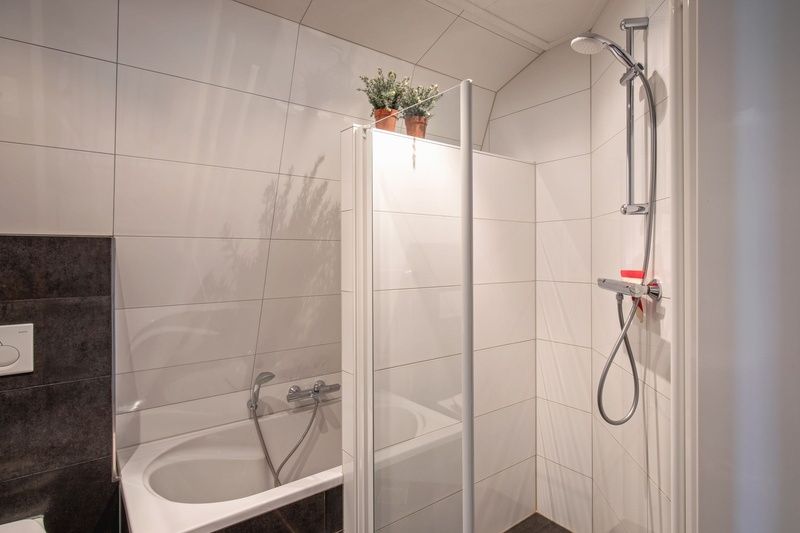 Villa Magnifique in Den Burg, Texel: modernes Badezimmer mit Dusche und Badewanne in einem frischen, weissen Stil.