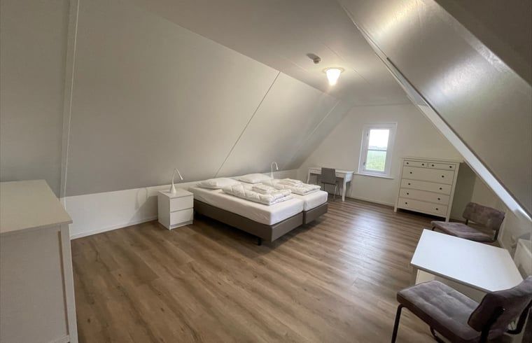 Spacious bedroom with wooden floor in Cottage in Den Burg, Texel, for a comfortable stay.