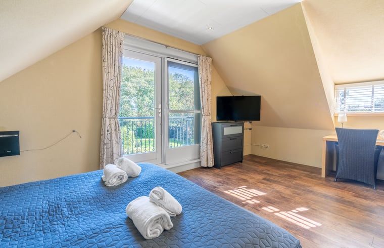 Helles Schlafzimmer im Ferienhaus in Den Burg, Texel, mit Arbeitsplatz und TV.