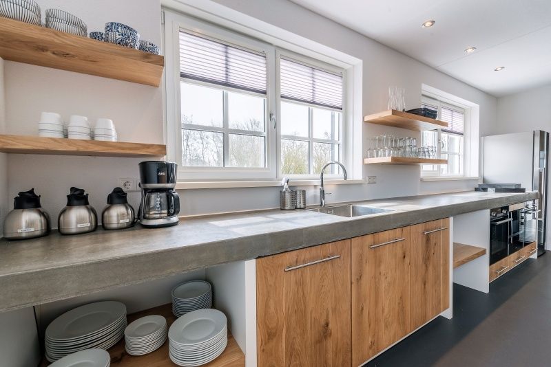 Moderne Kueche in der Gruppenunterkunft Nieuw Leven 36p, Ferienhaus Texel, mit Holzschraenken und grosszuegigen Arbeitsflaechen.