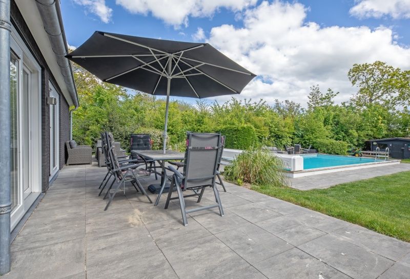 Spacious terrace of Villa 3C in Den Burg, Texel, with parasol and garden furniture, ideal vacation home for outdoor living.