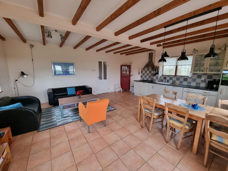 Wohnzimmer des Ferienhauses Duinzicht Den Burg Texel mit gemuetlicher Sitzecke und offener Kueche.