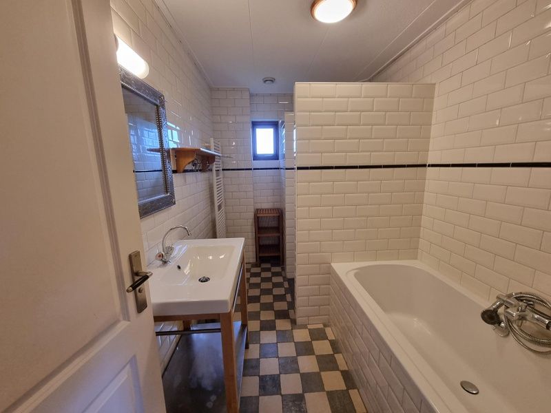 Modernes Badezimmer im Ferienhaus Duinzicht Den Burg Texel mit Badewanne und stilvollen Fliesen.