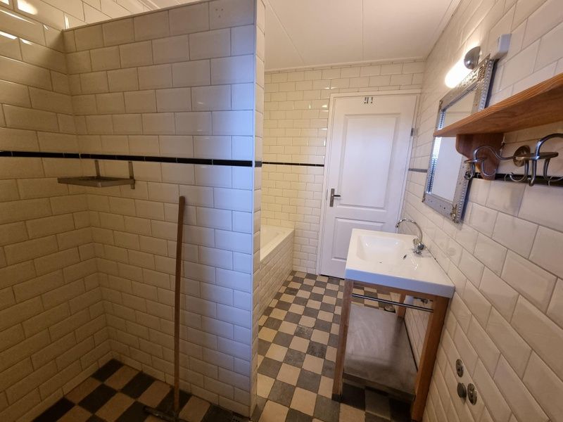 Stilvolles Badezimmer im Ferienhaus Duinzicht Den Burg Texel mit Dusche und weissen Fliesen.