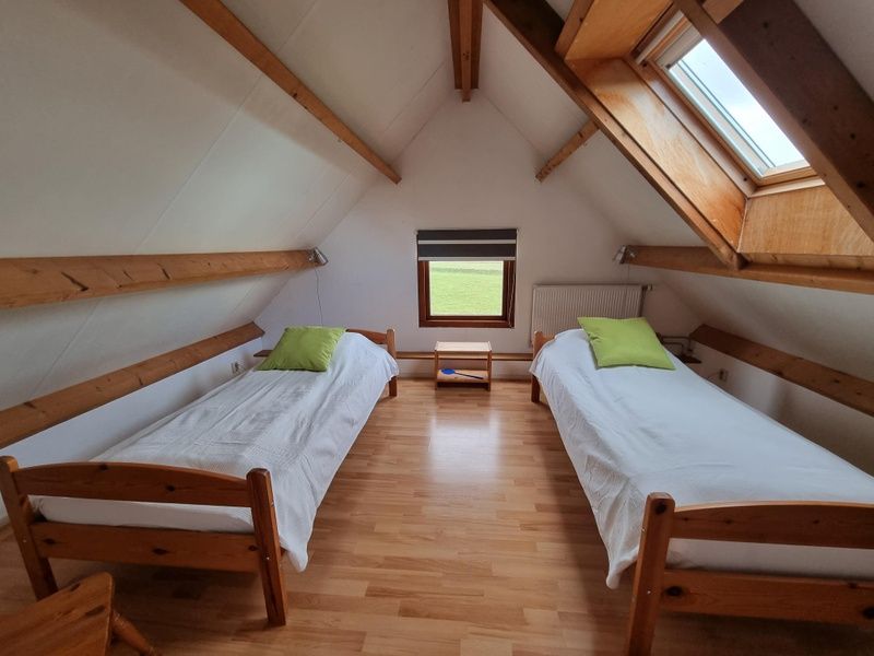 Mansardenzimmer im Ferienhaus Duinzicht Den Burg Texel mit zwei Einzelbetten und Dachfenster.