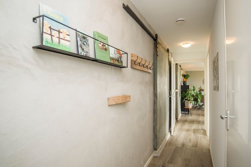 Stijlvolle gang in Onder de Wol vakantiehuis Texel met boekenplank en kunst.