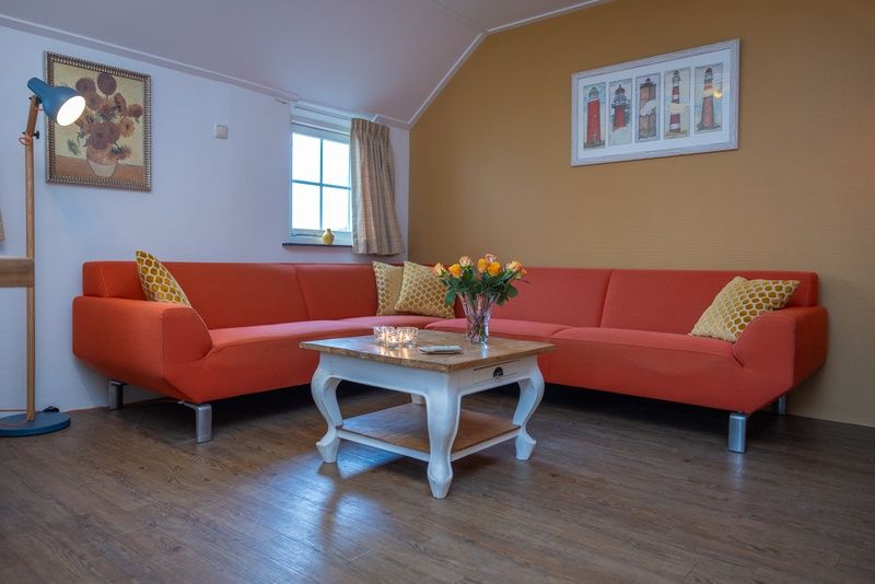 Gemuetliches Wohnzimmer von Apartment Yellow in Den Hoorn, Texel. Komfortables Ferienhaus auf den Watteninseln mit gemuetlicher Sitzecke und rustikalen Moebeln.