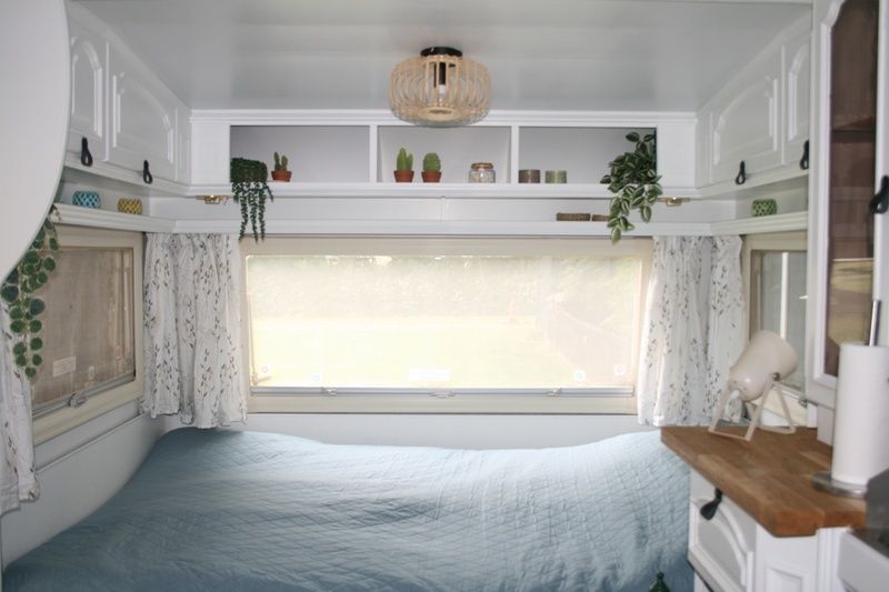 Schlafbereich im Caravan Rust & Ruimte, Den Hoorn, Texel, mit grossem Fenster und gemuetlicher Einrichtung.