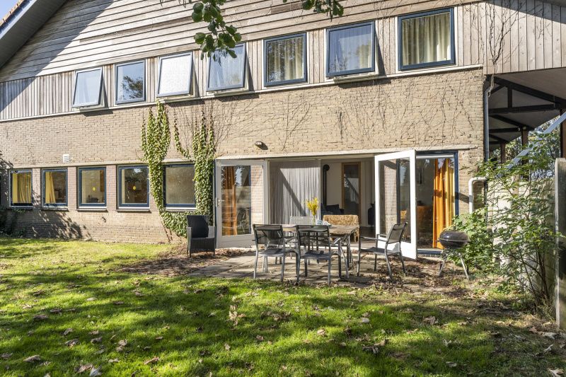 Aussenterrasse des Ferienhauses Sil in Den Hoorn, Texel mit Gartenmoebeln und gruener Umgebung.