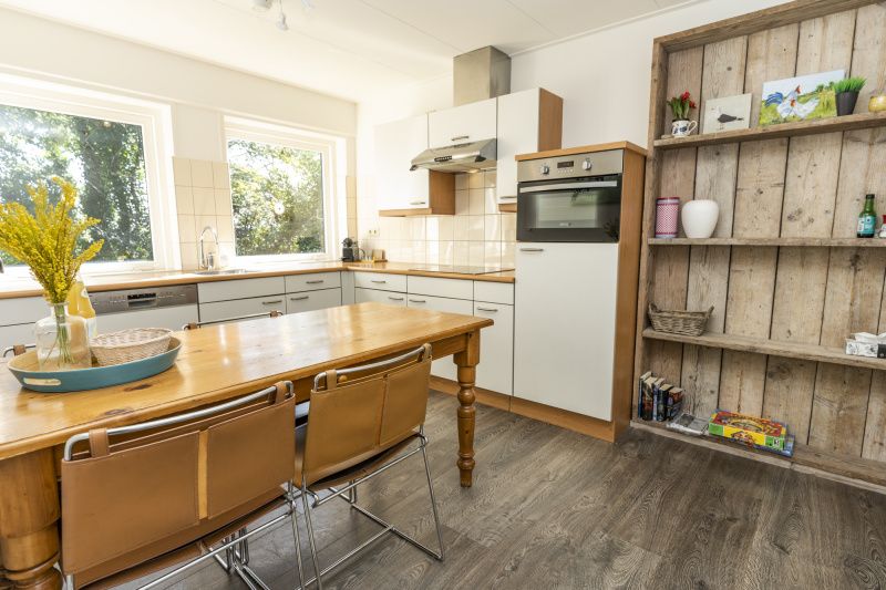 Geraeumige Kueche des Ferienhauses Sil, Den Hoorn, Texel mit Esstisch und Gartenblick.