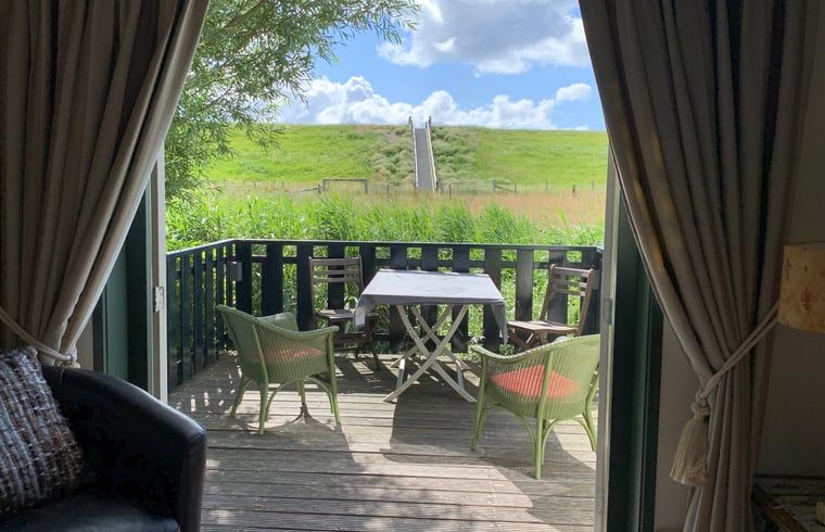 View from the terrace of Holiday home in Oosterend, Texel, with green surroundings and blue sky.